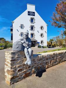 a statue of a man sitting on a wall in front of a building at The Originals City, Hôtel Armen Le Triton, Roscoff in Roscoff