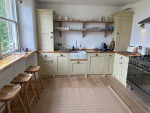 a kitchen with white cabinets and wooden stools at Dilkusha, Peebles in Peebles