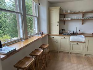 a kitchen with wooden stools and a counter with windows at Dilkusha, Peebles in Peebles
