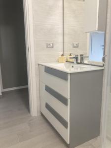 a white kitchen with a sink and a mirror at La Casa di EMMA in Corsico