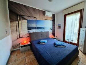 a bedroom with a blue bed with a large window at Al mare da Iva in Duna Verde