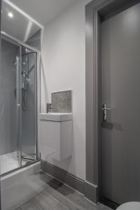 a bathroom with a glass shower and a sink at Lugton Rooms in Beith