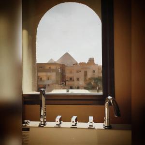 een wastafel in de badkamer met een raam met uitzicht op een gebouw bij Zahira Pyramids View in Caïro