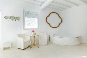 Un baño blanco con bañera y espejo redondo. en Nikis Home, en Mykonos ciudad