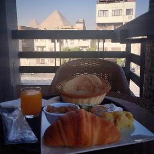 una mesa con un plato de comida y un vaso de zumo de naranja en Zahira Pyramids View en El Cairo