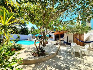 un patio con un árbol y sillas y una piscina en Pousada Suítes do Atlântico en Ilhéus