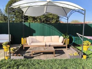 un sofá blanco bajo una sombrilla en un patio en Herama Garden Guesthouse, en Vila Nova de Gaia