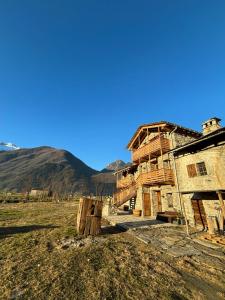 an old building in a field with mountains in the background at Chalet Valchiavenna in San Cassiano