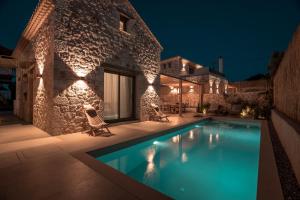 a villa with a swimming pool at night at PAPADRIA VILLAS - Modern Luxury villas near Kathisma Beach in Tsoukaladhes
