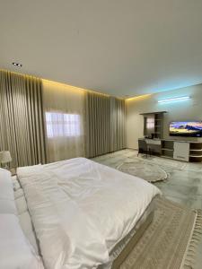 a bedroom with a large white bed and a flat screen tv at مشار العلا AL ULA in AlUla