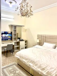 a bedroom with a bed and a desk and a chandelier at مشار العلا AL ULA in AlUla