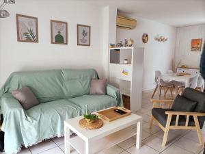 a living room with a green couch and a table at Fleur De Sel in Gruissan