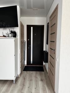 a hallway with a black door and a television at Likos apartamentai in Anykščiai