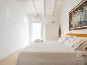 - une chambre blanche avec un grand lit et une peinture murale dans l'établissement Casa Giovele, à Selargius