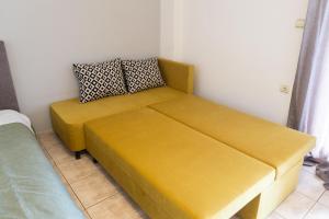 a yellow couch in a room with a bed at Elia mini suites 5 in Larisa