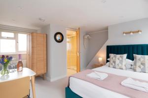 1 dormitorio con cama, escritorio y reloj en Cosy Loft Retreat, King Bed, En-suite, Kitchenette, Homestay en Brighton & Hove