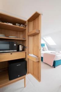 Habitación con cama y armario con microondas. en Cosy Loft Retreat, King Bed, En-suite, Kitchenette, Homestay en Brighton & Hove