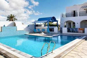 a swimming pool with chairs in front of a house at 5 bedrooms villa with private pool enclosed garden and wifi at Djerba 1 km away from the beach in Houmt Souk