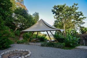 a tent in a garden with a bench and a table at Quimera Glamping in Pacuar