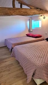1 Schlafzimmer mit 2 Betten mit rosa Bettwäsche und einem Fenster in der Unterkunft Le P'tit Gîte d'Isa, 15 km du Puy du Fou in Mauléon