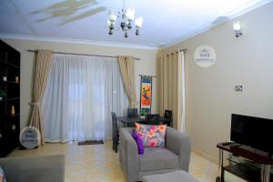 sala de estar con silla y TV en Haz Holiday Home en Kampala