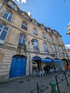 a large building with blue doors and tables and chairs at Appartement de charme sous les toits avec vue sur la Garonne in Bordeaux +12 photos