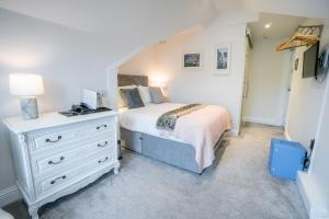 a bedroom with a white bed and a dresser at Trefoil Guest House in Brixham
