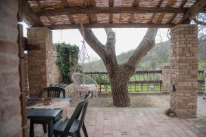 a patio with a table and chairs and a tree at La casa del Colle in San Ginesio