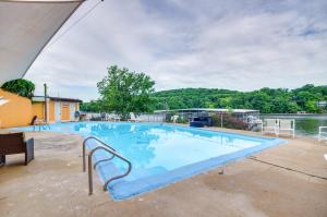 a large blue swimming pool next to a body of water at Cozy Lake Ozark Condo Rental with Grill, Pool Access in Lake Ozark