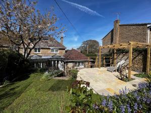 einen Garten mit einer hölzernen Pergola vor einem Haus in der Unterkunft East Cottage in Weymouth