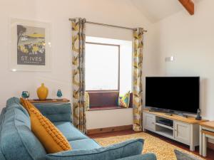 un soggiorno con divano blu e TV di Long Barn a Penzance
