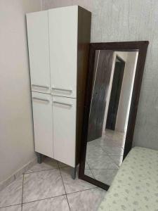 Apartamento 5 km do aeroporto في برازيليا: خزانة بيضاء ومرآة في الغرفة