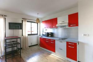 - une cuisine avec des placards rouges et une table dans l'établissement 32 m love nest studio with balcony, à Paris