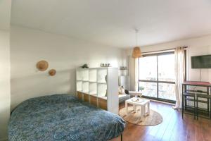 a bedroom with a bed and a tv and a window at 32 m love nest studio with balcony in Paris