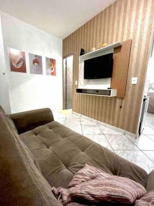 Apartamento 5 km do aeroporto في برازيليا: غرفة معيشة مع أريكة وتلفزيون بشاشة مسطحة