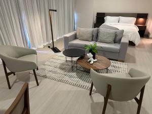 ein Wohnzimmer mit einem Bett, einem Sofa und Stühlen in der Unterkunft Arcadia Condo Suites in Panama-Stadt