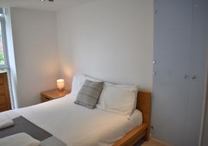 a bedroom with a bed with white sheets and pillows at Cawley Priory - Family Friendly, City Centre Apartment, Sleeps 4 in Chichester