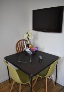 a black table with two yellow chairs and a television at Canal Walk - Chichester City Centre Apartment in Chichester