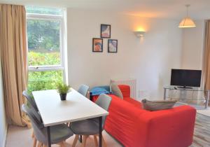 a living room with a red couch and a table at Chichester Quarters - Ground Floor, City Centre, 2 Bedroom Apartment in Chichester
