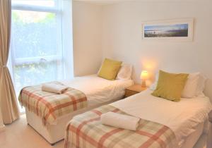 two beds in a room with a window at Chichester Quarters - Ground Floor, City Centre, 2 Bedroom Apartment in Chichester