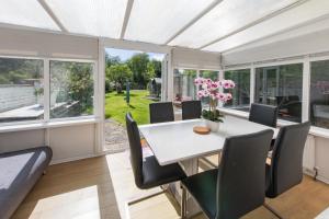 a dining room with a table and chairs and windows at Cosy Family Home in Ruislip in Ruislip