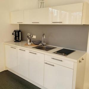 a kitchen with white cabinets and a sink at Appartment Düne 6 1OG Grundbelegung 2 Pers in Elsterheide