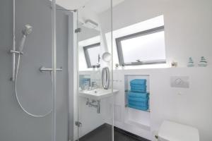 a white bathroom with a shower and a sink at Appartment Düne 6 1OG Grundbelegung 2 Pers in Elsterheide