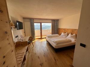 um quarto de hotel com uma cama e uma grande janela em Hotel Elisabeth Panorama em Antermoia
