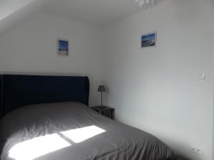 a bed in a room with a white wall at Comme chez vous in Le Crotoy