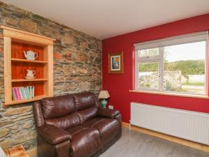 a living room with a leather couch and a window at Curragh Cottage 