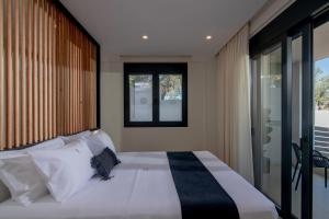 a bedroom with a bed with white pillows and a window at Anantia Luxury Maisonette - Scenic View in episkopi-heraklion