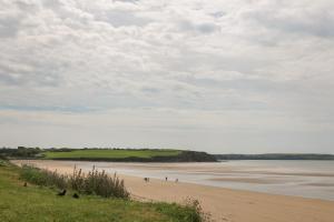 a beach with people standing on it next to the water at Curragh Cottage 