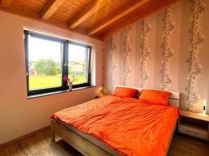 um quarto com uma cama com um edredão laranja e uma janela em Wohnung in Schmidt mit Grill und Garten em Nideggen