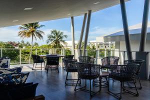 a patio with chairs and tables and palm trees at Casas Refúgio da Barra in Barra Grande